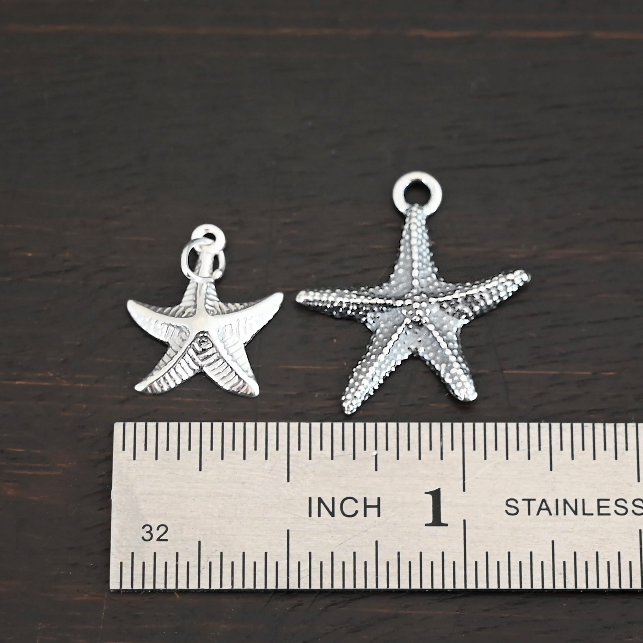 Silver star fish charms shown by ruler