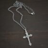 Silver crucifix pendant charm shown on chain on dark background