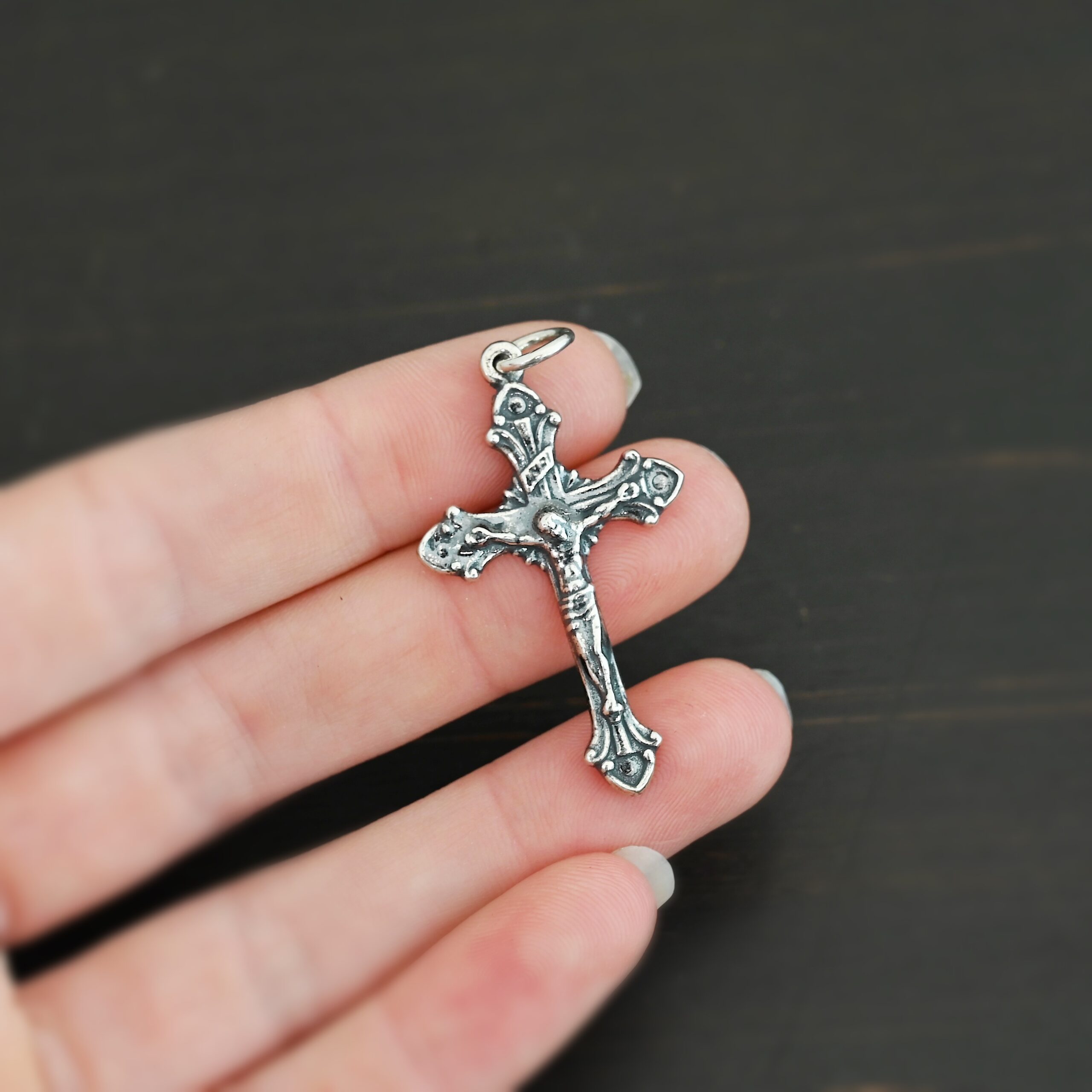 Silver crucifix pendant charm shown in hand