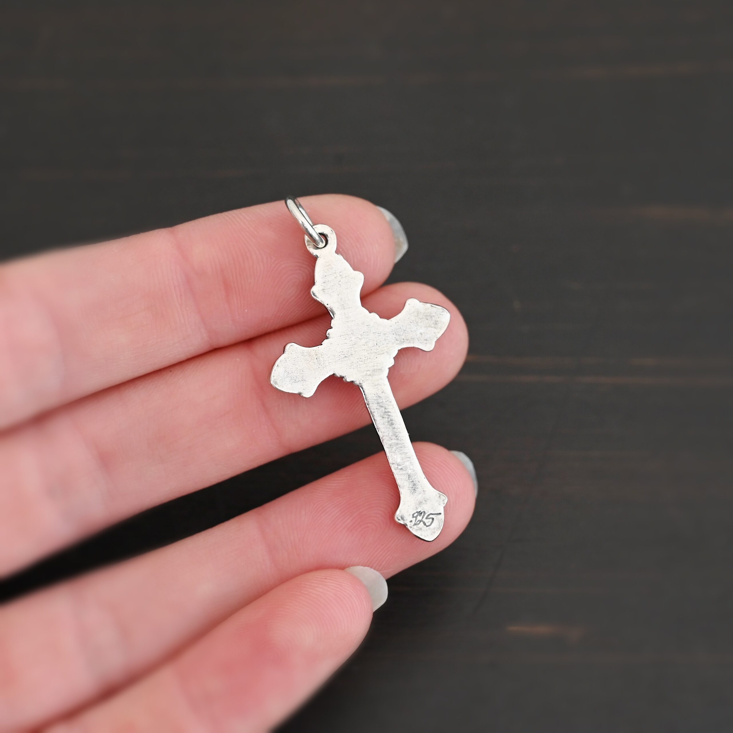 back side of Silver crucifix pendant charm shown in hand