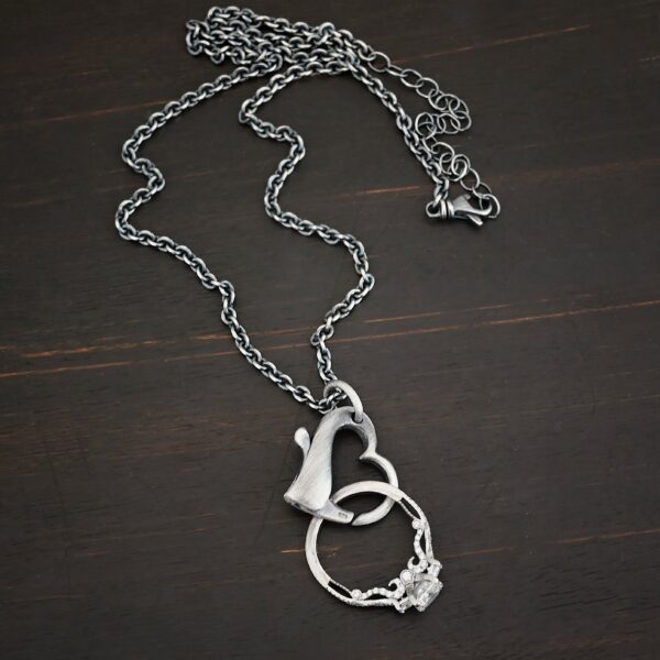 Silver heart charm oxidized pendant necklace shown on dark background