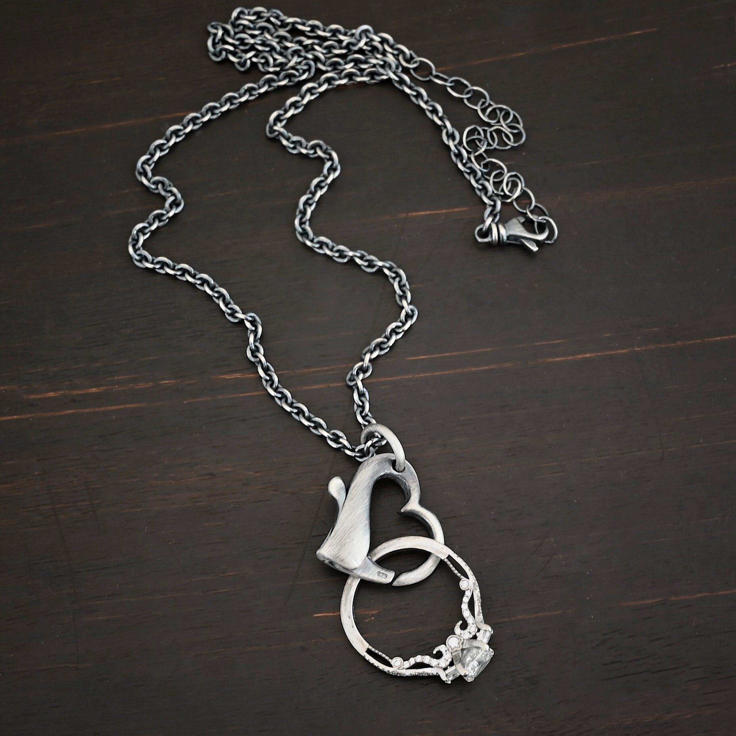 Silver heart charm oxidized pendant necklace shown on dark background