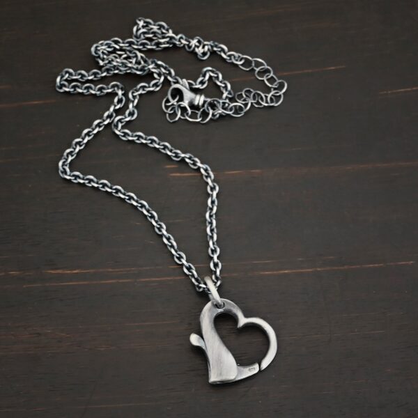Silver heart charm oxidized pendant necklace shown on dark background