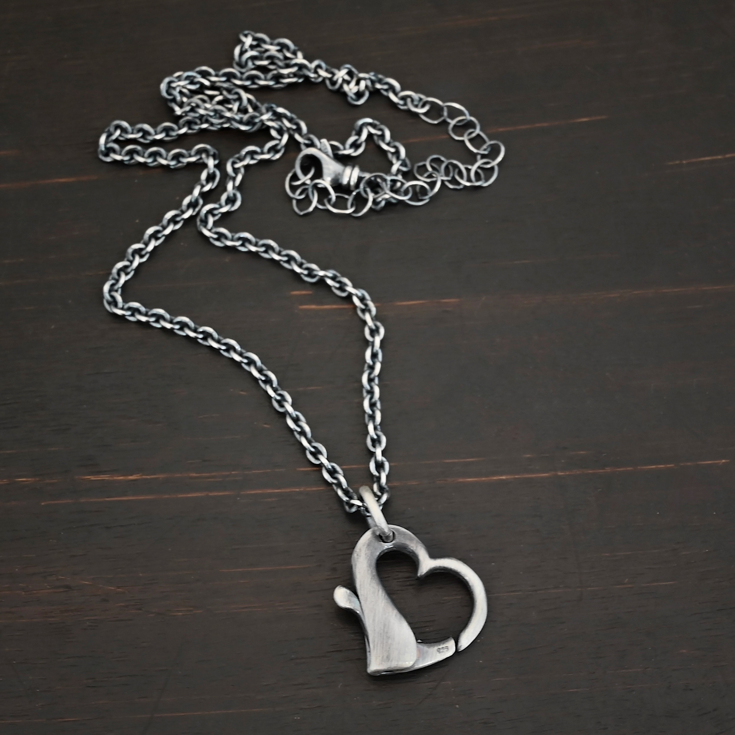 Silver heart charm oxidized pendant necklace shown on dark background