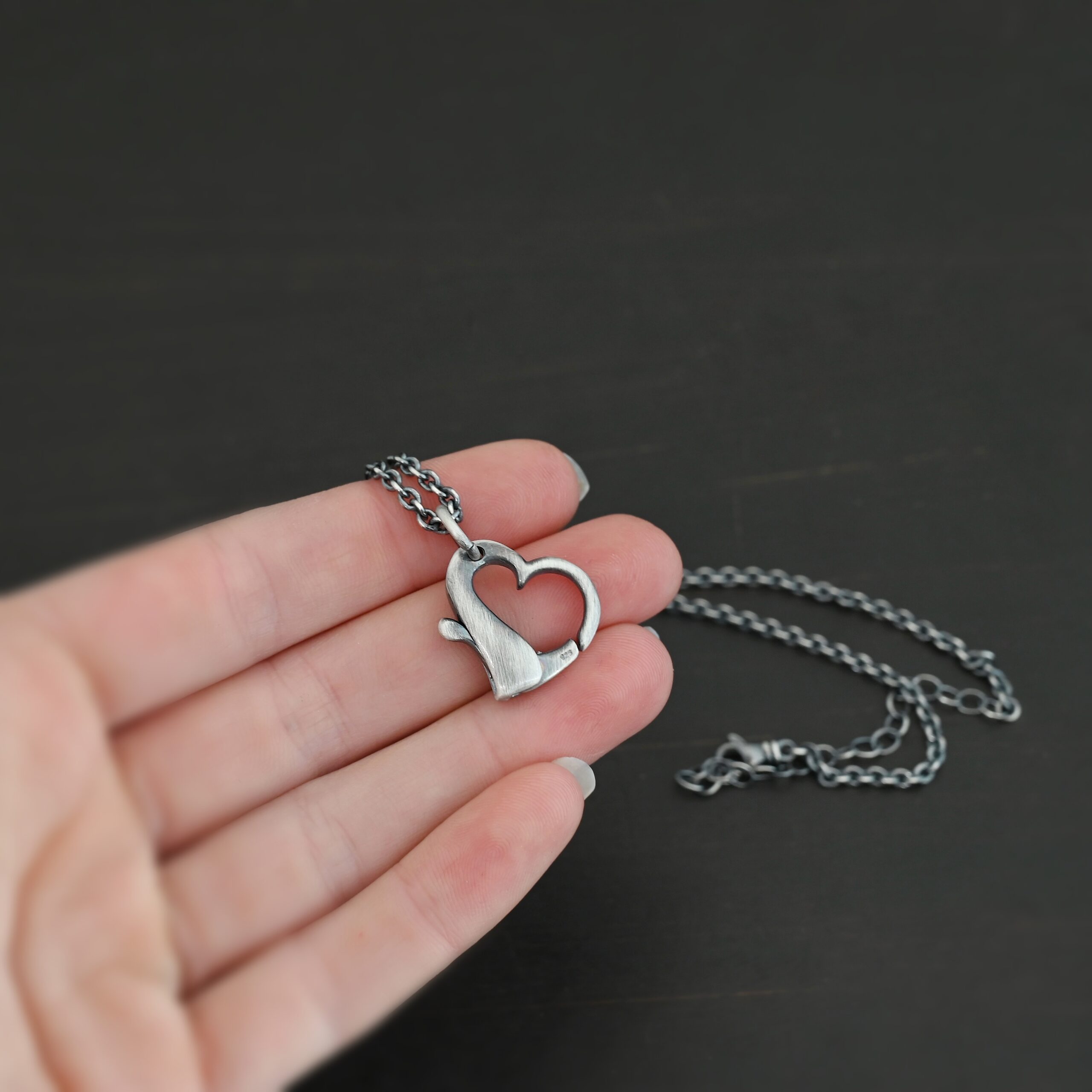 Silver heart charm oxidized pendant necklace shown in hand