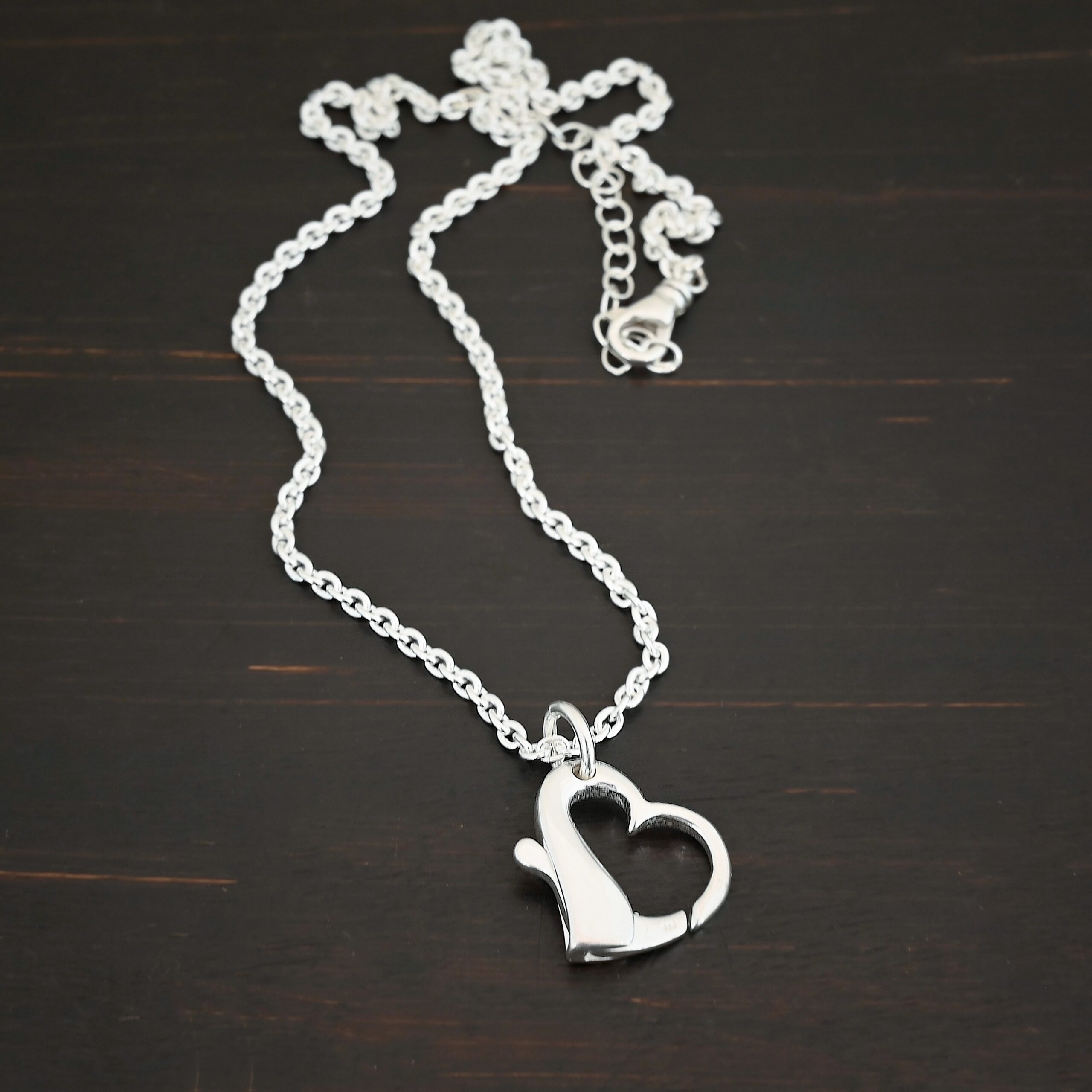 Silver heart charm shiny pendant necklace shown on dark background