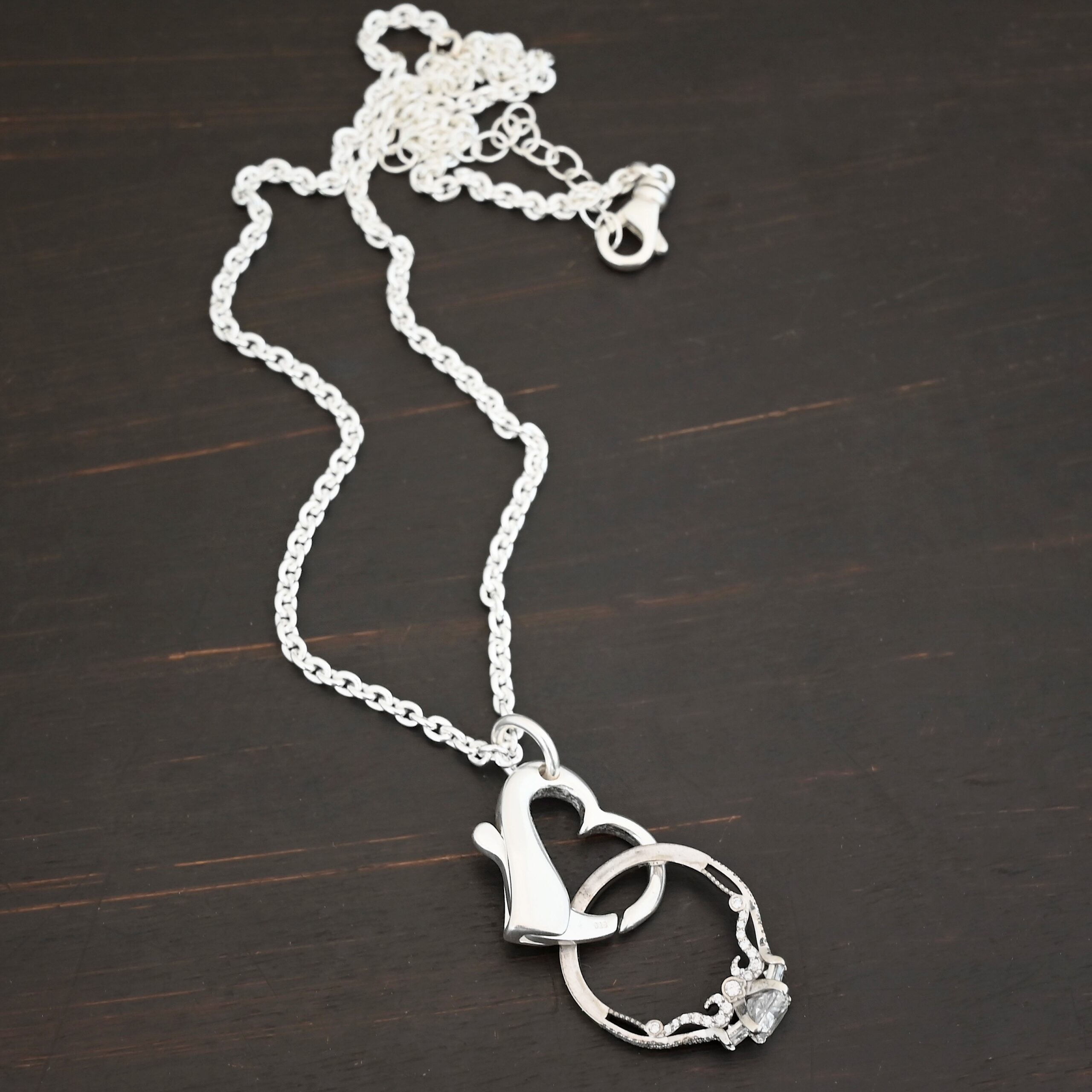 Silver heart charm shiny pendant necklace shown on dark background