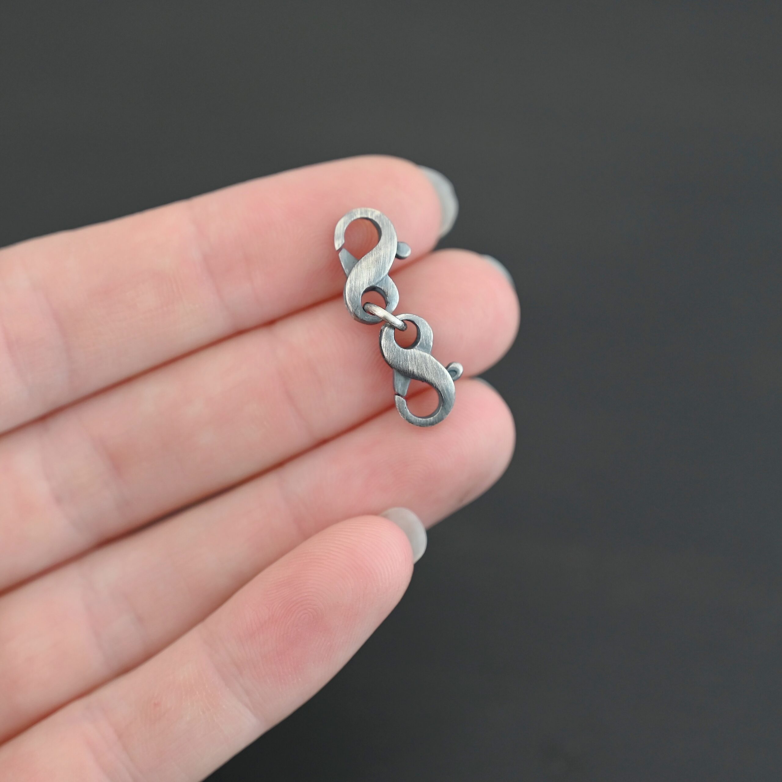 Faith double figure 8 clasp - oxidized shown in hand