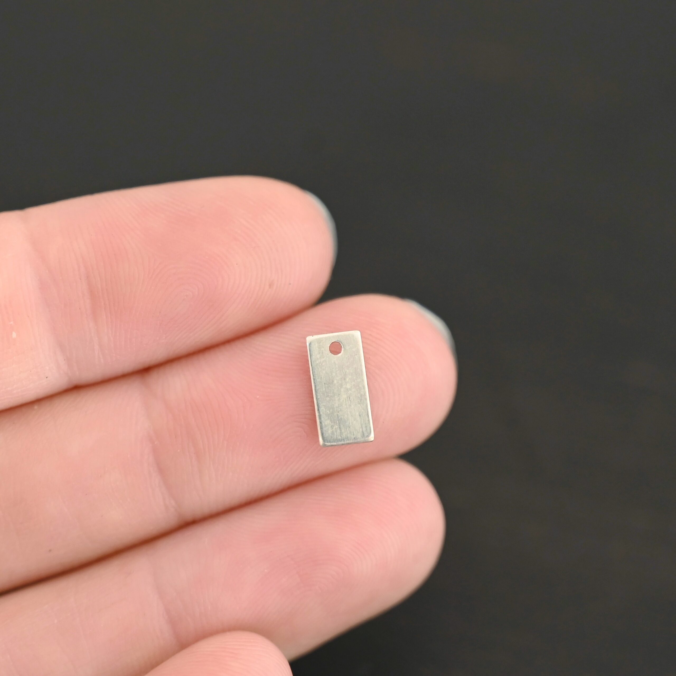 Sterling Silver small rectangle blank - shiny smooth 1 hole shown in hand