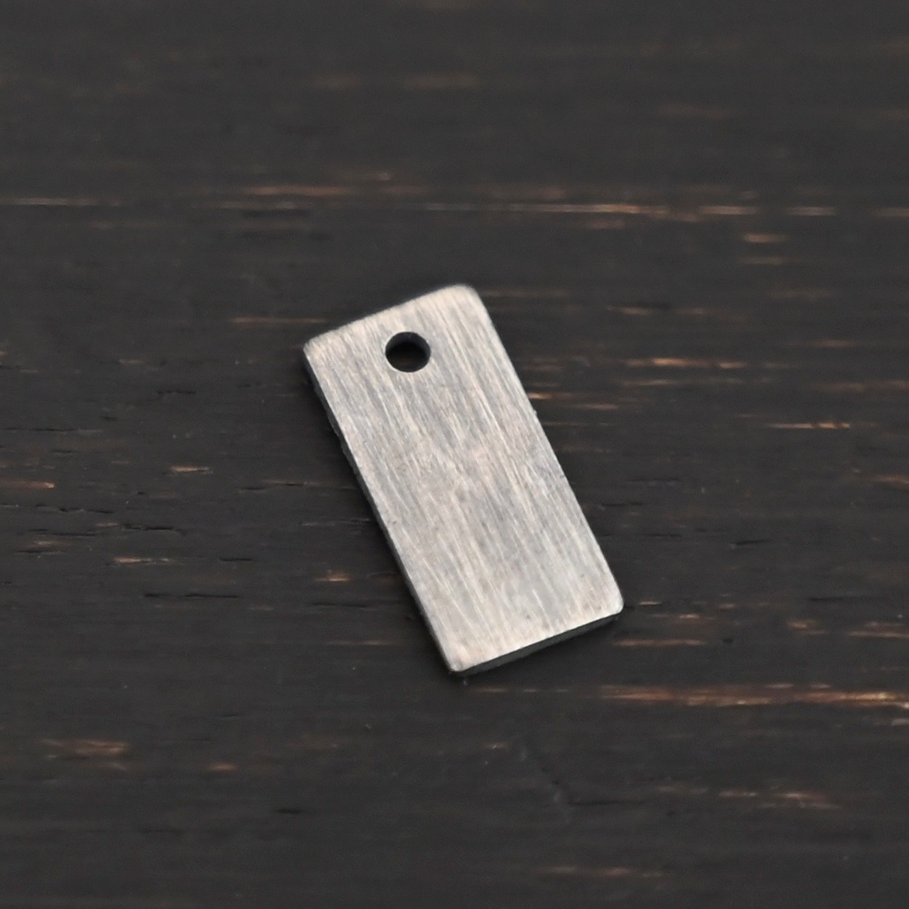 Sterling Silver small rectangle blank - oxidized smooth 1 hole shown on dark background
