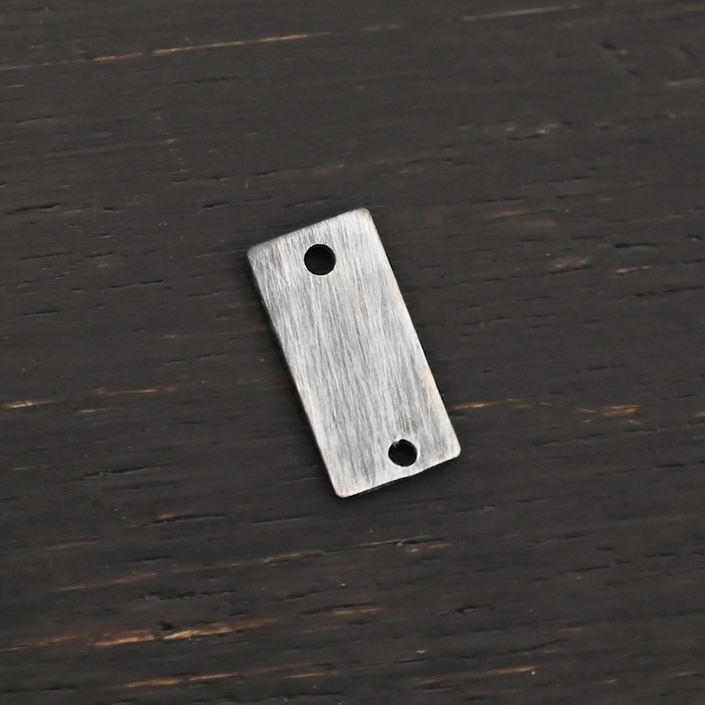 Sterling Silver small rectangle blank - oxidized smooth 2 holes shown on dark background