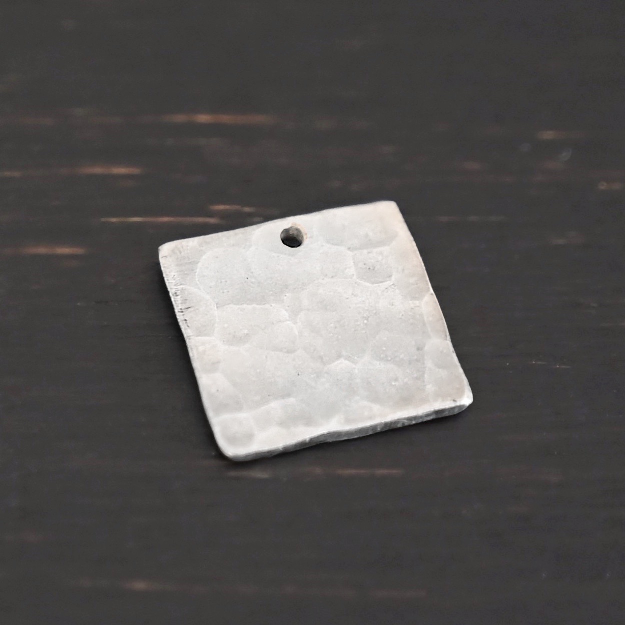 Hammered Square - shiny 1 hole Hammered Square - shiny 1 hole shown in dark background