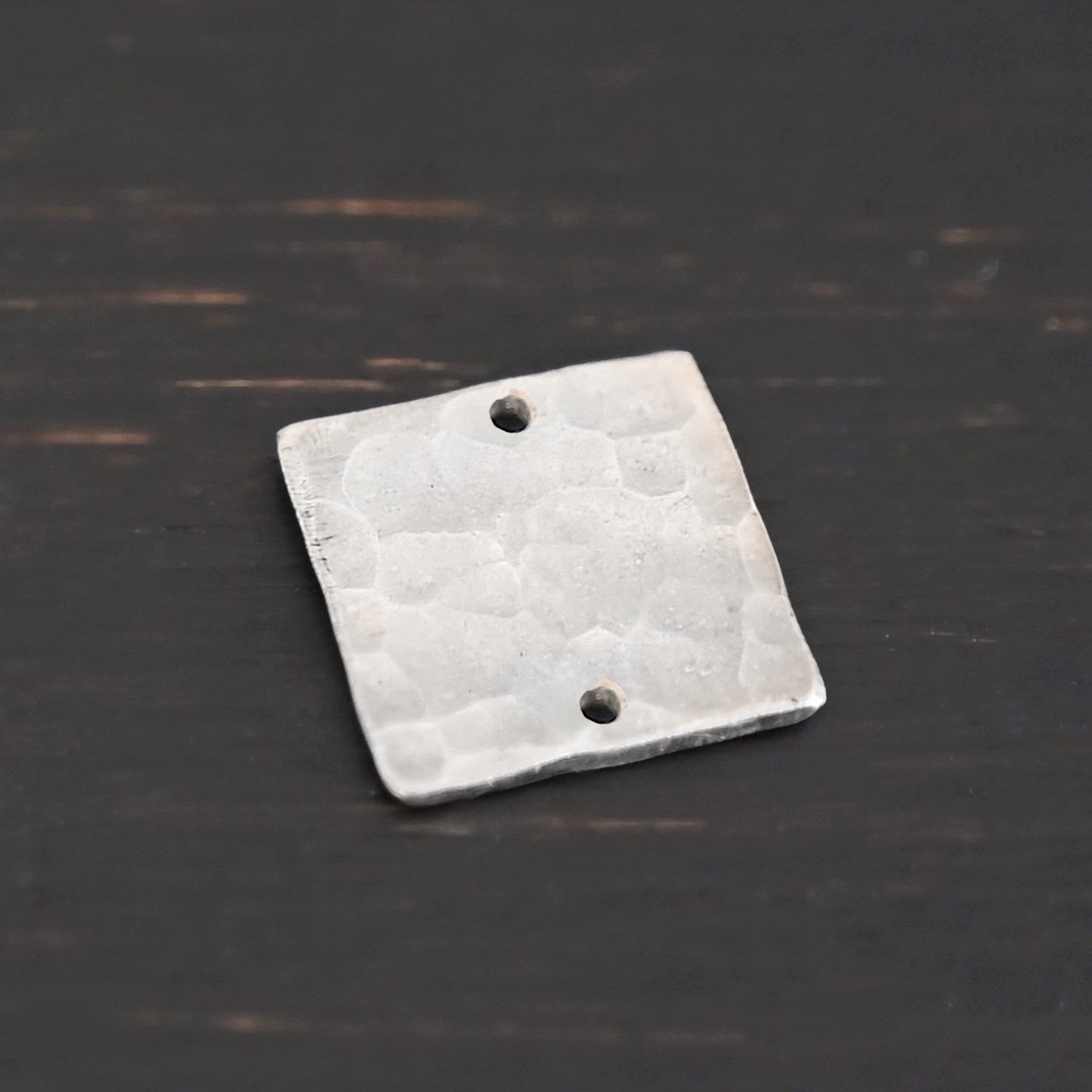 Hammered Square - shiny 2 holes Hammered Square - shiny 2 holes shown in dark background