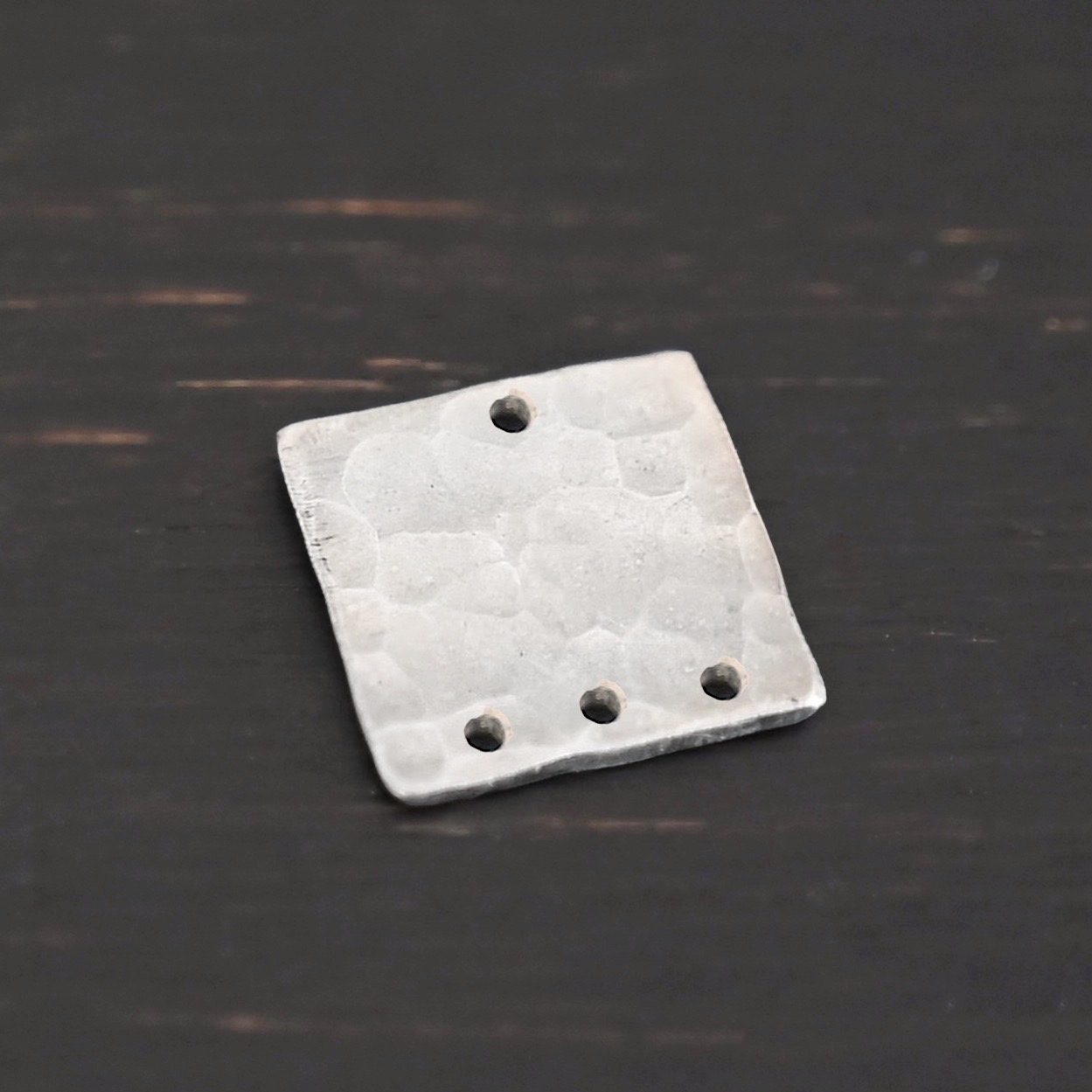 Hammered Square - shiny 4 holes Hammered Square - shiny 4 holes shown in dark background