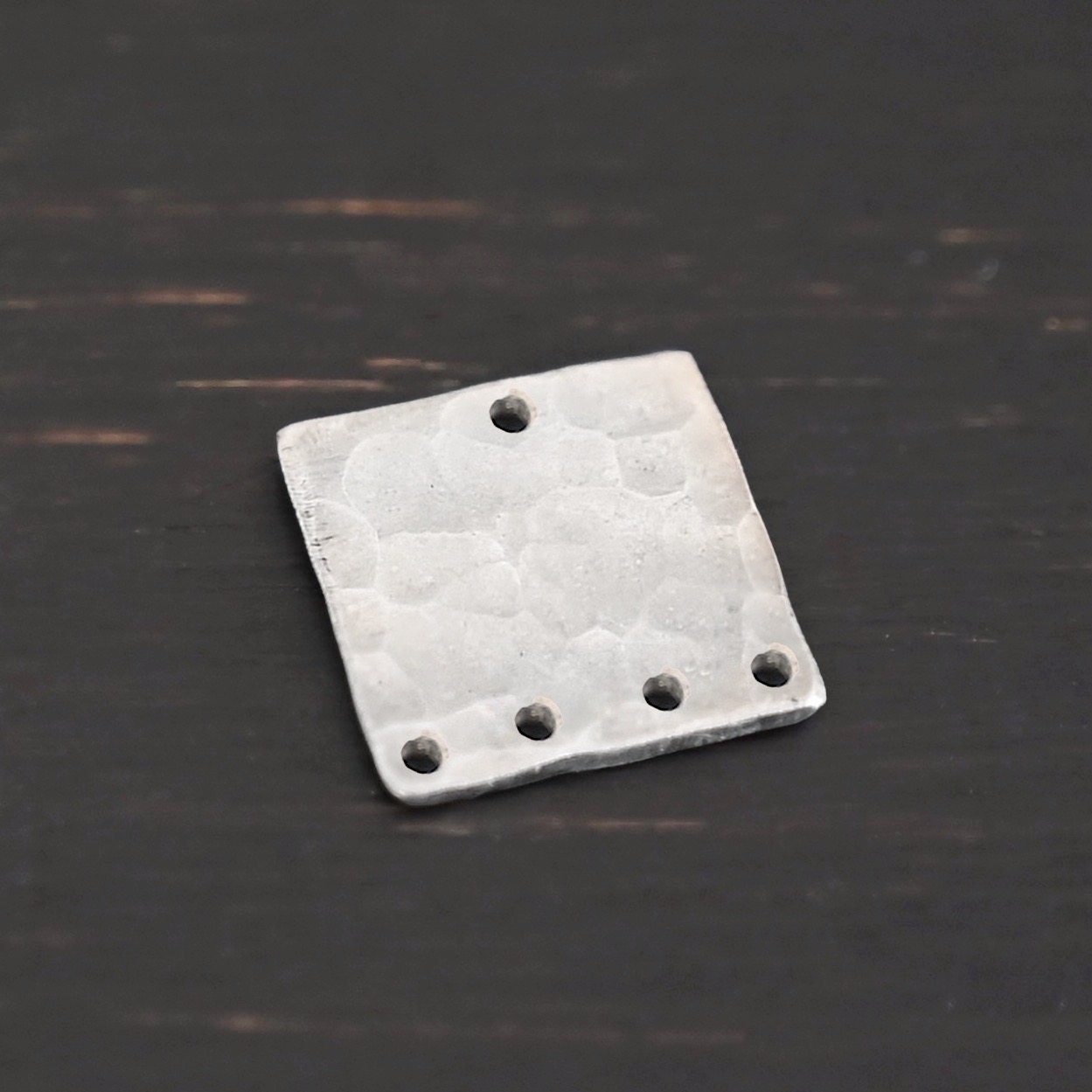 Hammered Square - shiny 5 holes Hammered Square - shiny 5 holes shown in dark background