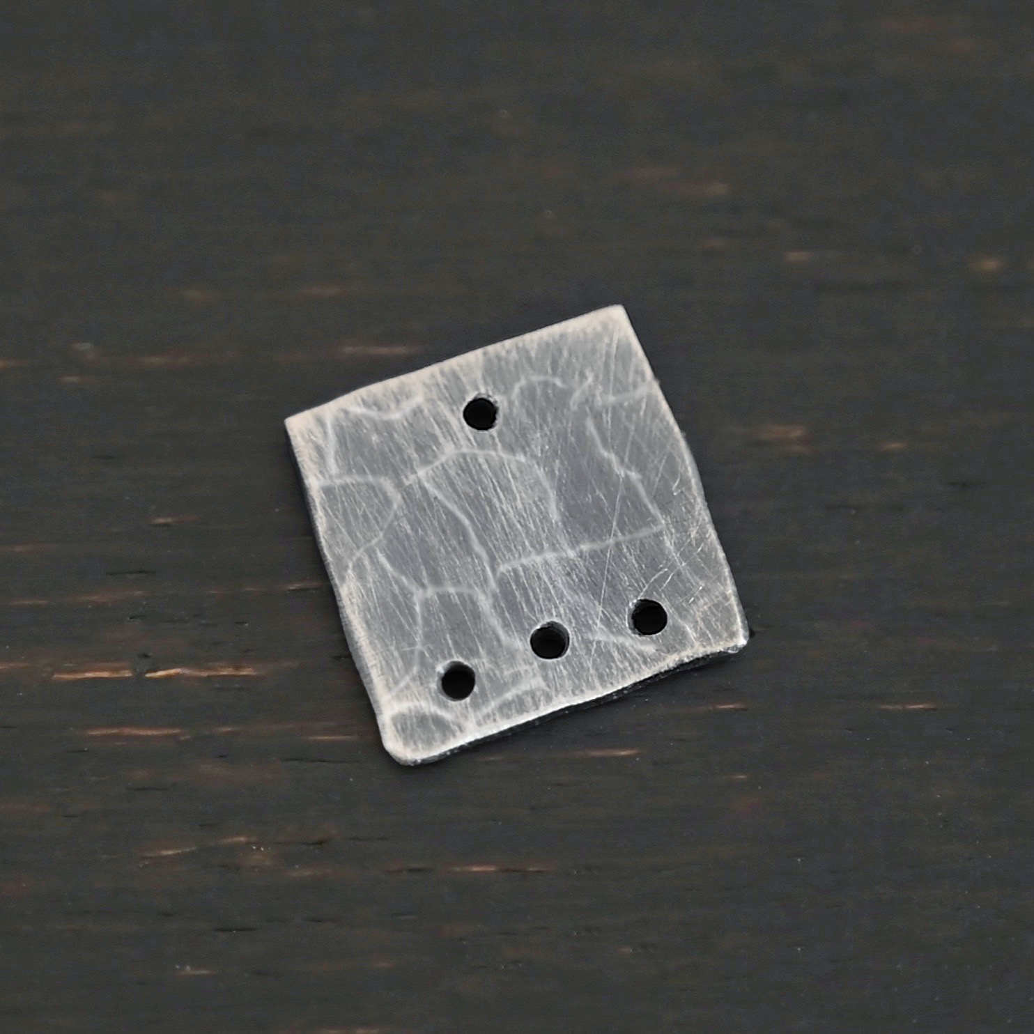 Hammered Square - oxidized 4 holes Hammered Square - oxidized 4 holes shown on dark background