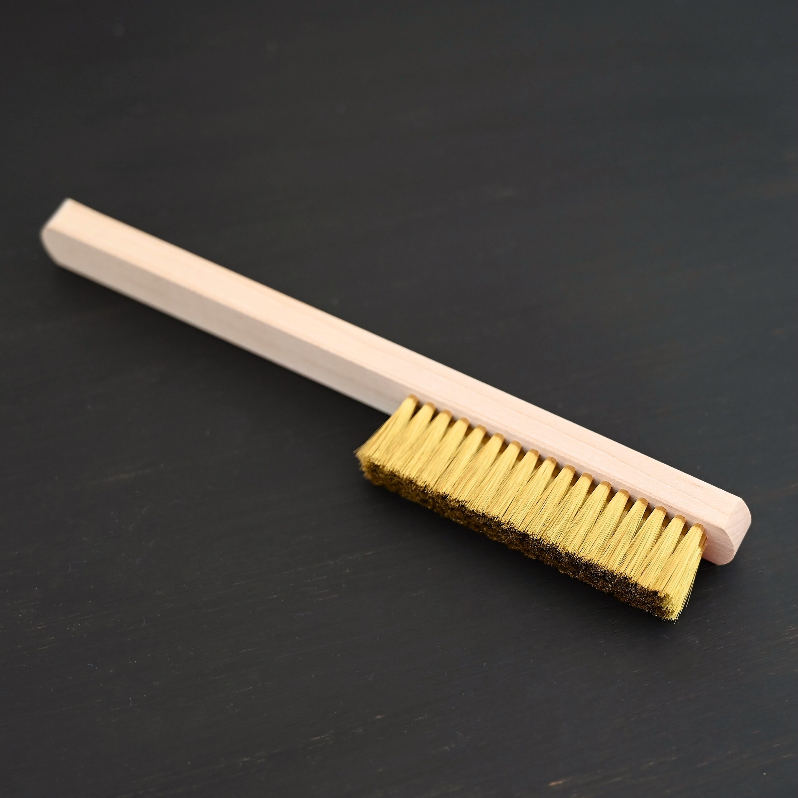 Brass Brush shown on dark background