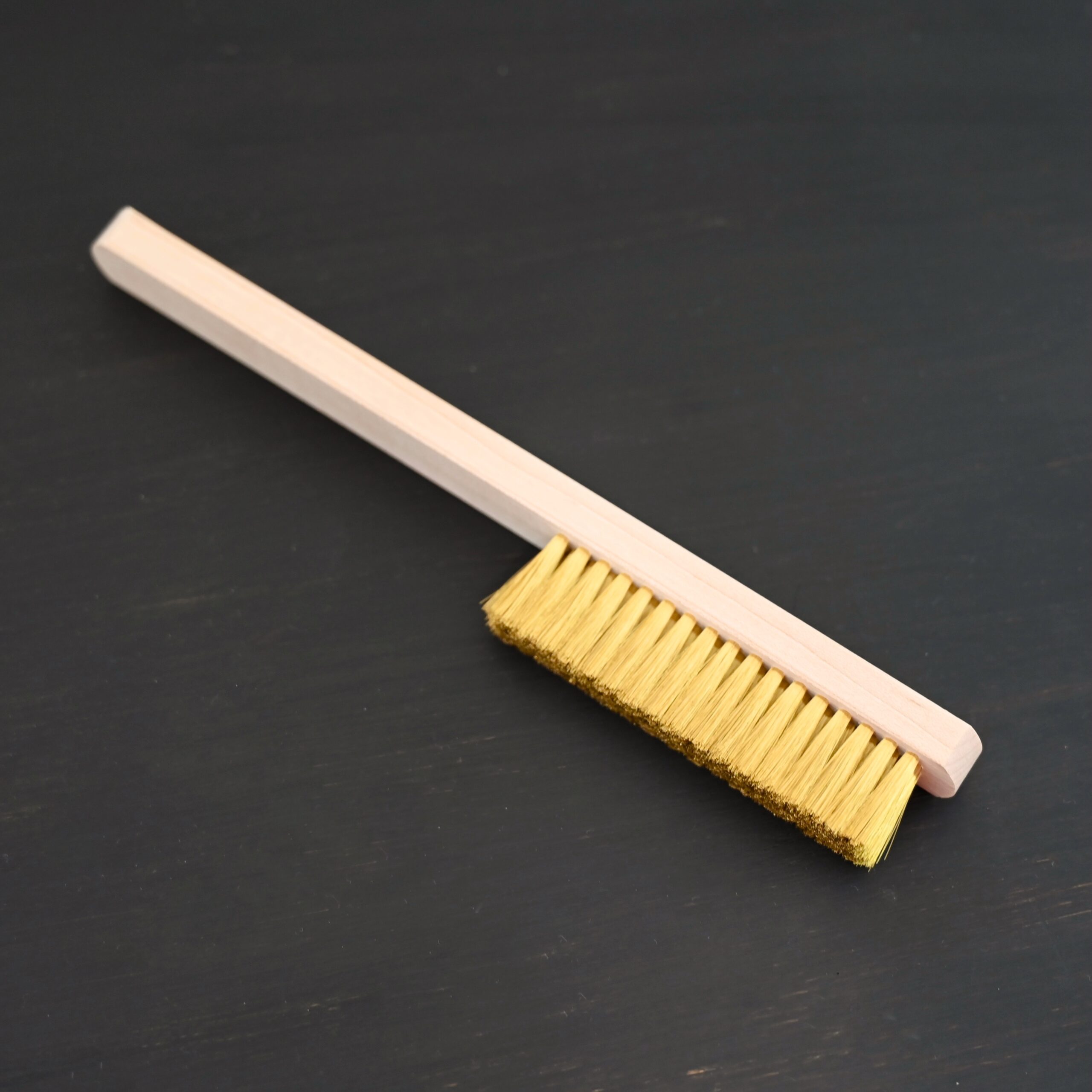 Brass Brush shown on dark background