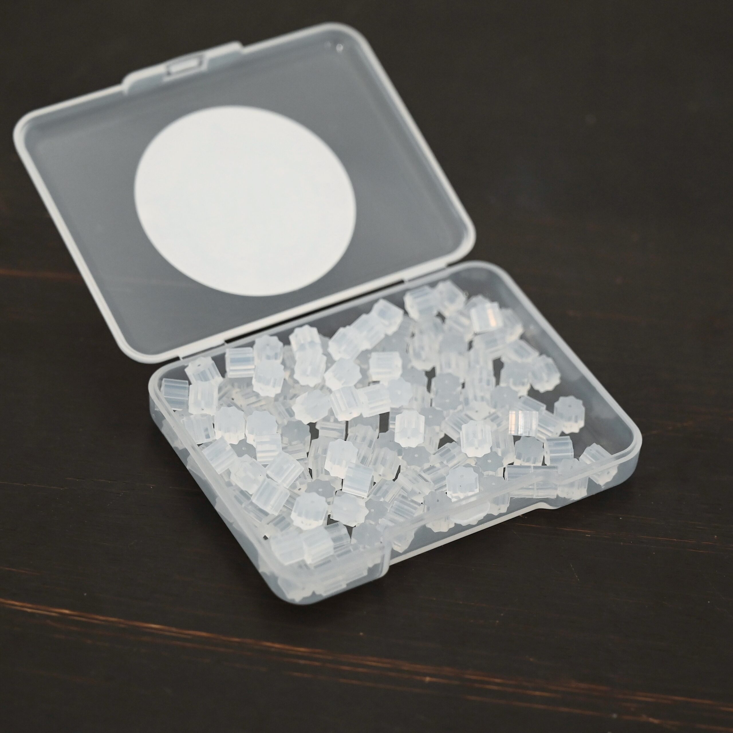 Rubber Earring Backs shown in plastic container on dark background