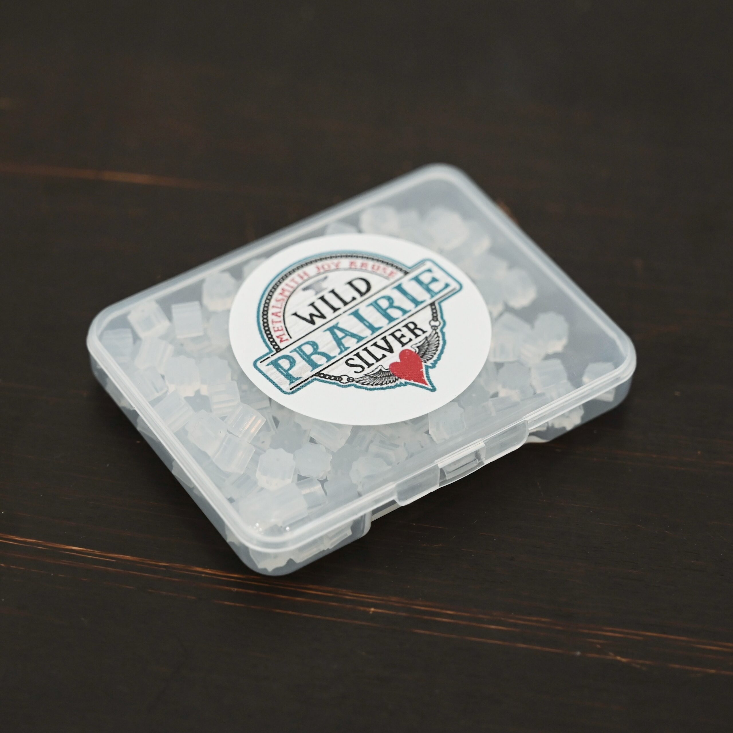 Rubber Earring Backs shown in plastic container on dark background