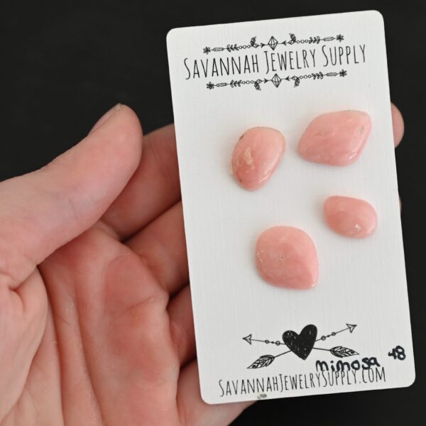 Mimosa Pink Opal cabochon parcel shown in hand