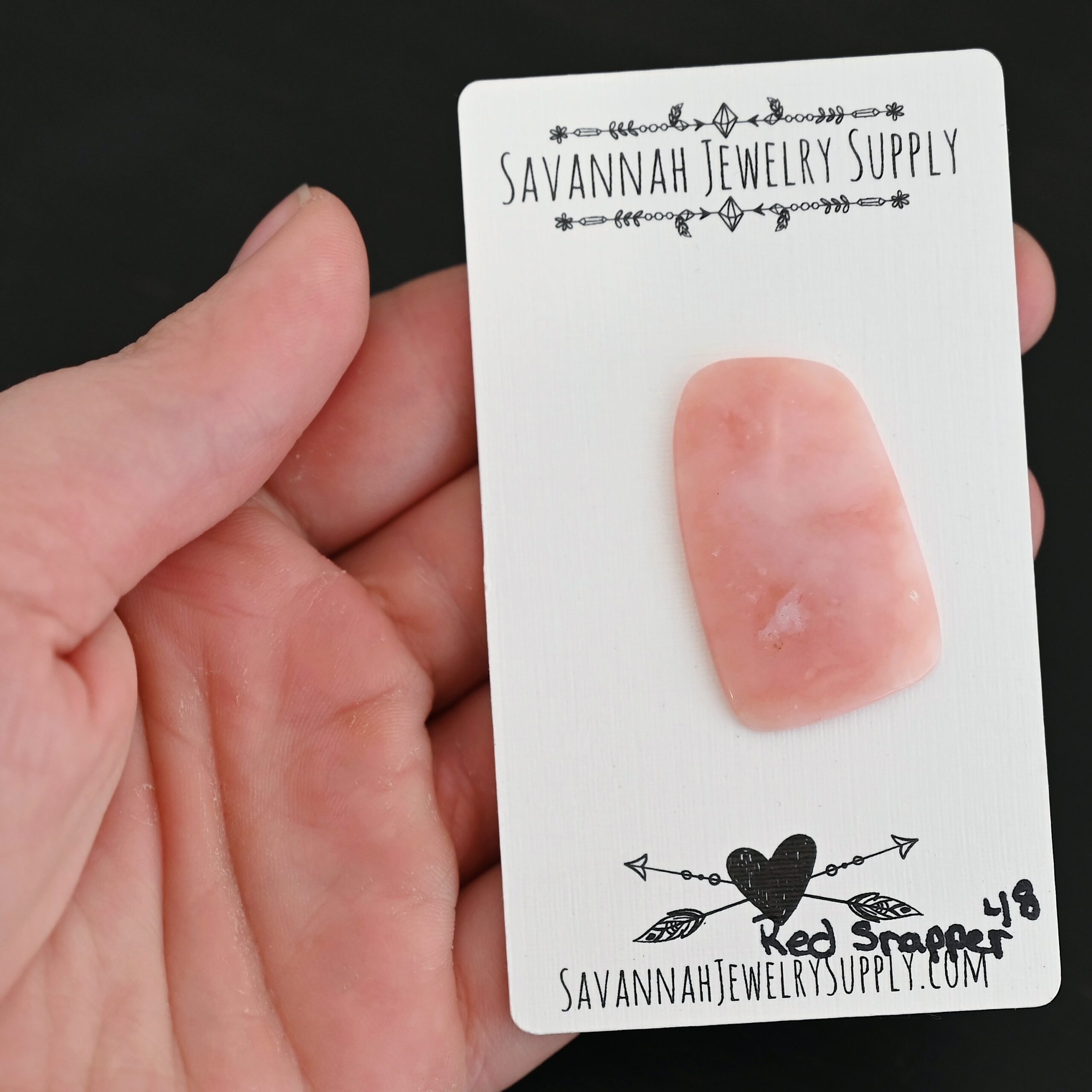 Red Snapper Pink Opal cabochon parcel shown in hand