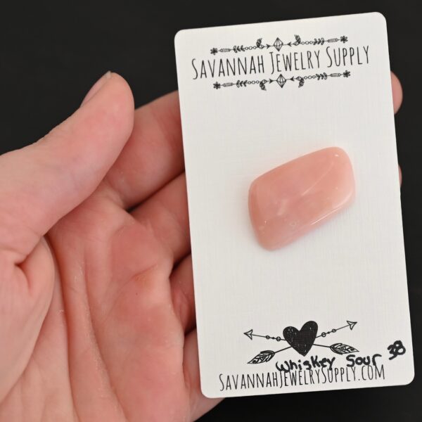 Whiskey Sour Pink Opal cabochon parcel shown in hand