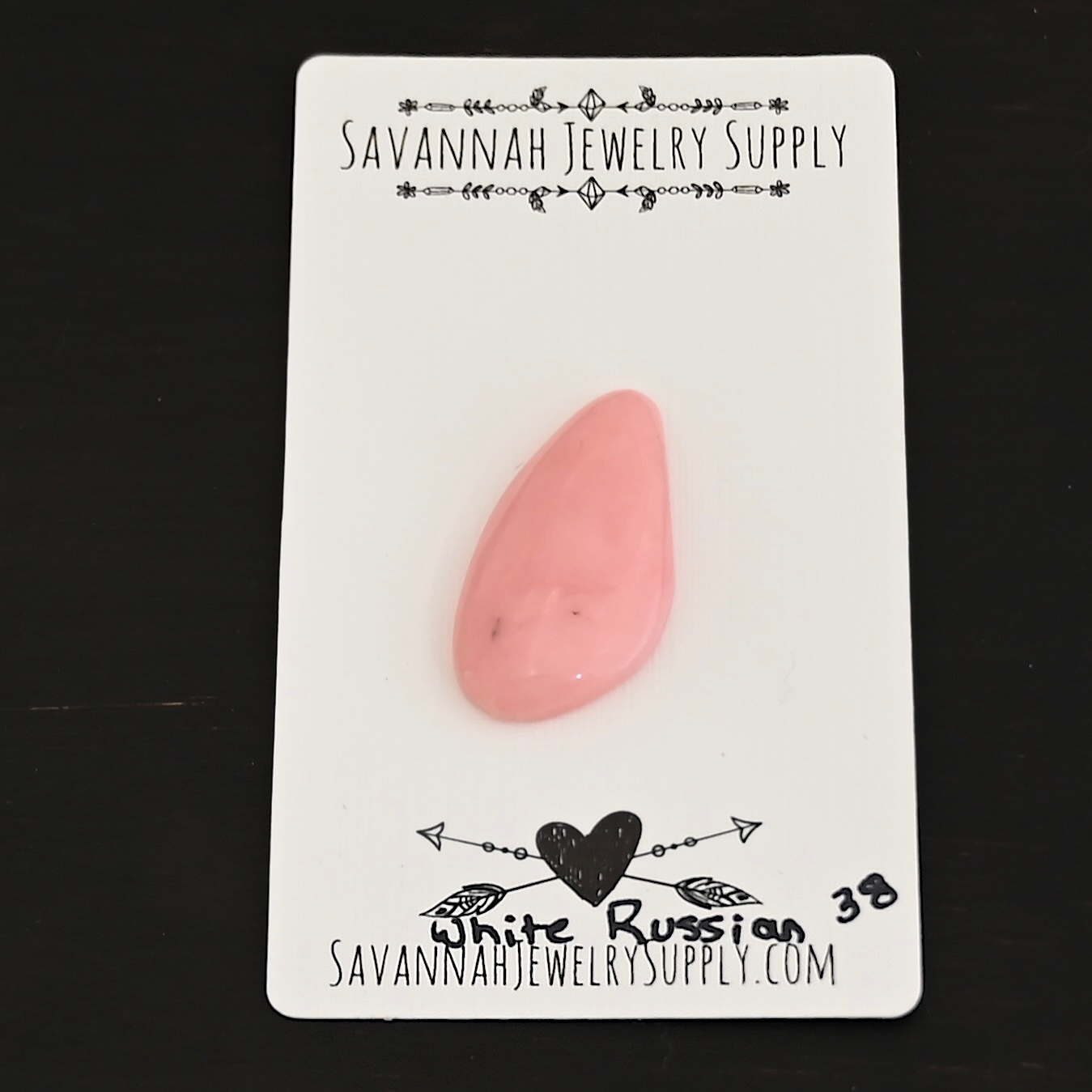 White Russian Pink Opal cabochon parcel shown on business card
