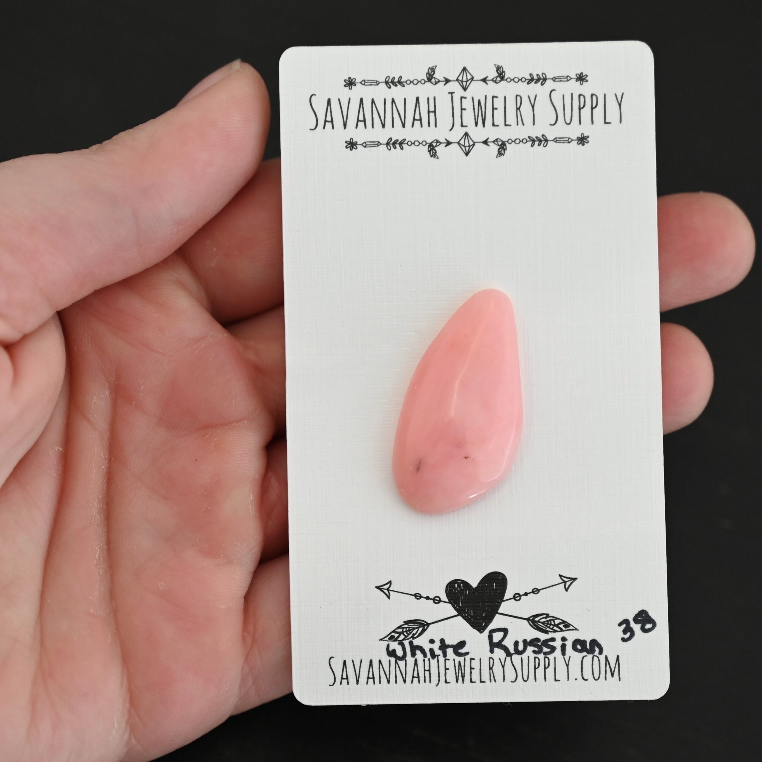 White Russian Pink Opal cabochon parcel shown in hand