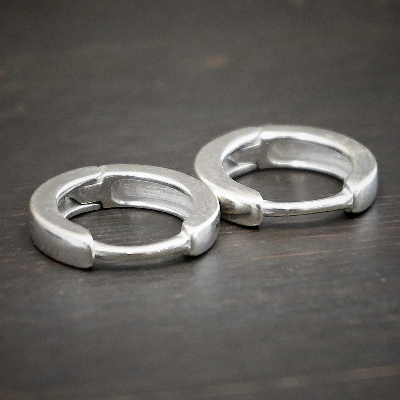 Winona Huggie Hoop Earrings - shiny sterling silver Winona Huggie Hoop Earrings - shiny shown on dark background