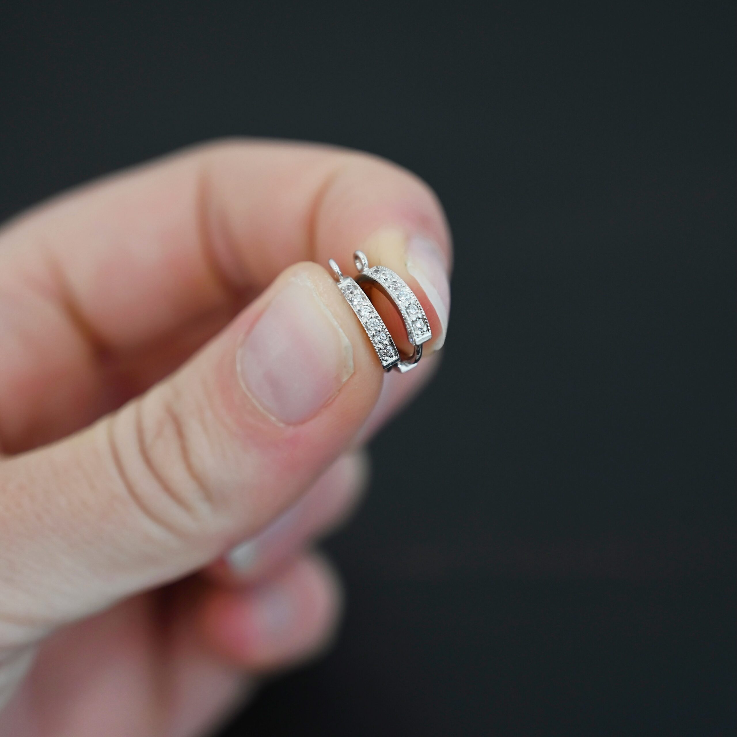 Rhodium Plated Sterling Silver Wisdom CZ Huggie Hoops shown in hand