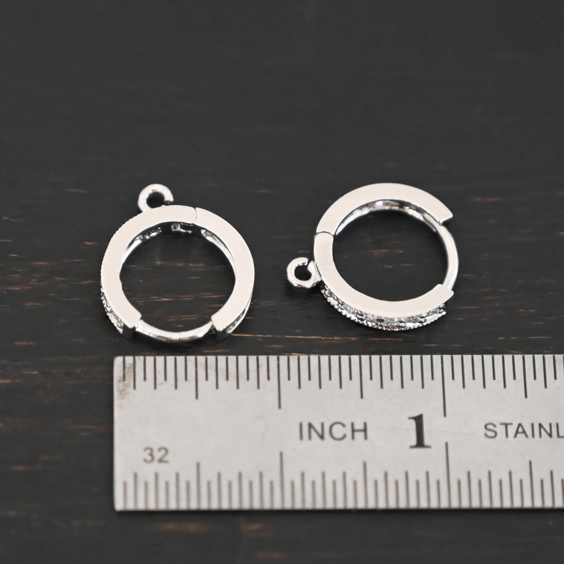 Rhodium Plated Sterling Silver Wisdom CZ Huggie Hoops shown by ruler