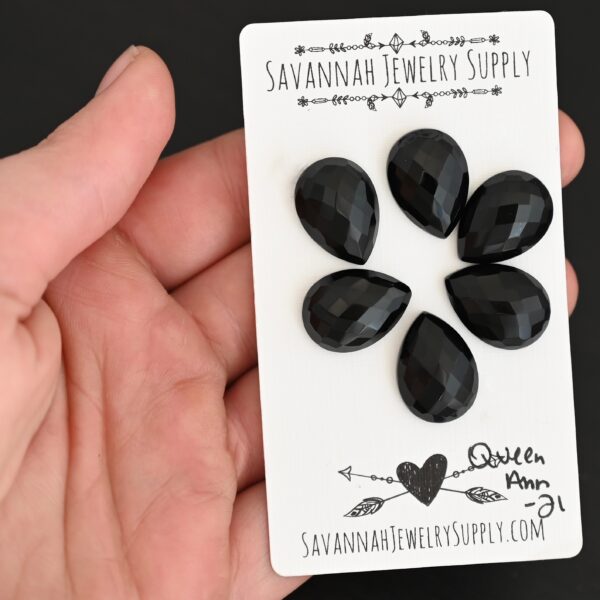 Queen Ann Rosecut Teardrop Black Onyx Cabochon Parcel shown in hand