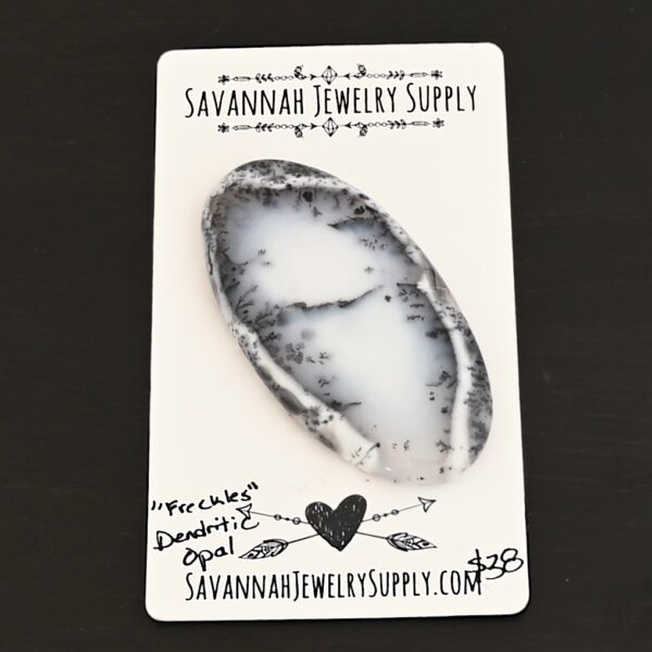 Freckles Dendritic Opal Cabochon shown on business card
