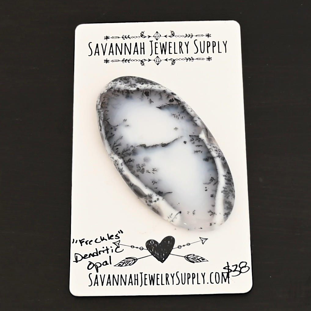 Freckles Dendritic Opal Cabochon shown on business card