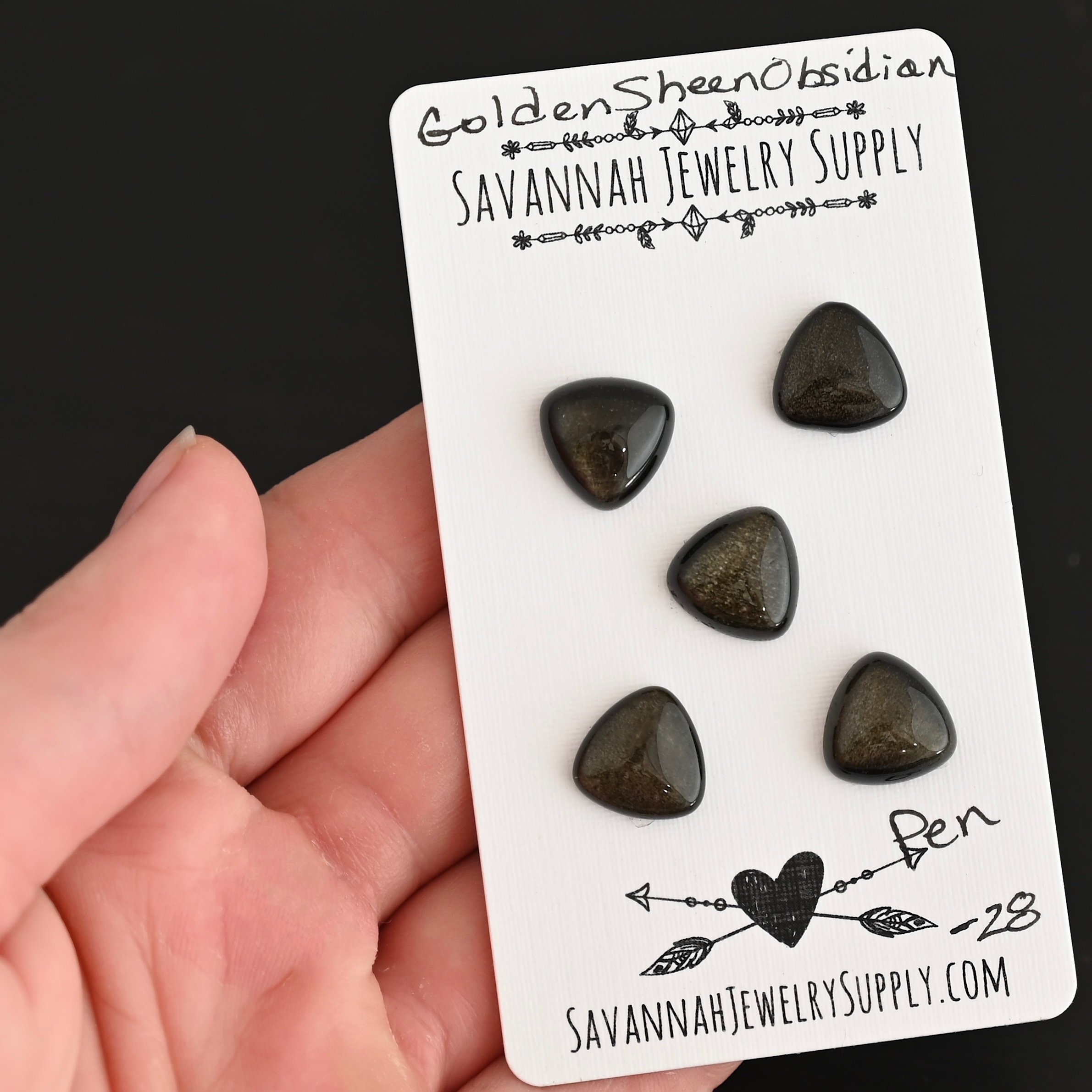 Pen Golden Sheen Obsidian Cabochon Parcel shown in hand