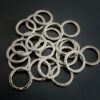 Pile of jump rings against a dark background. They are hammered and oxidized