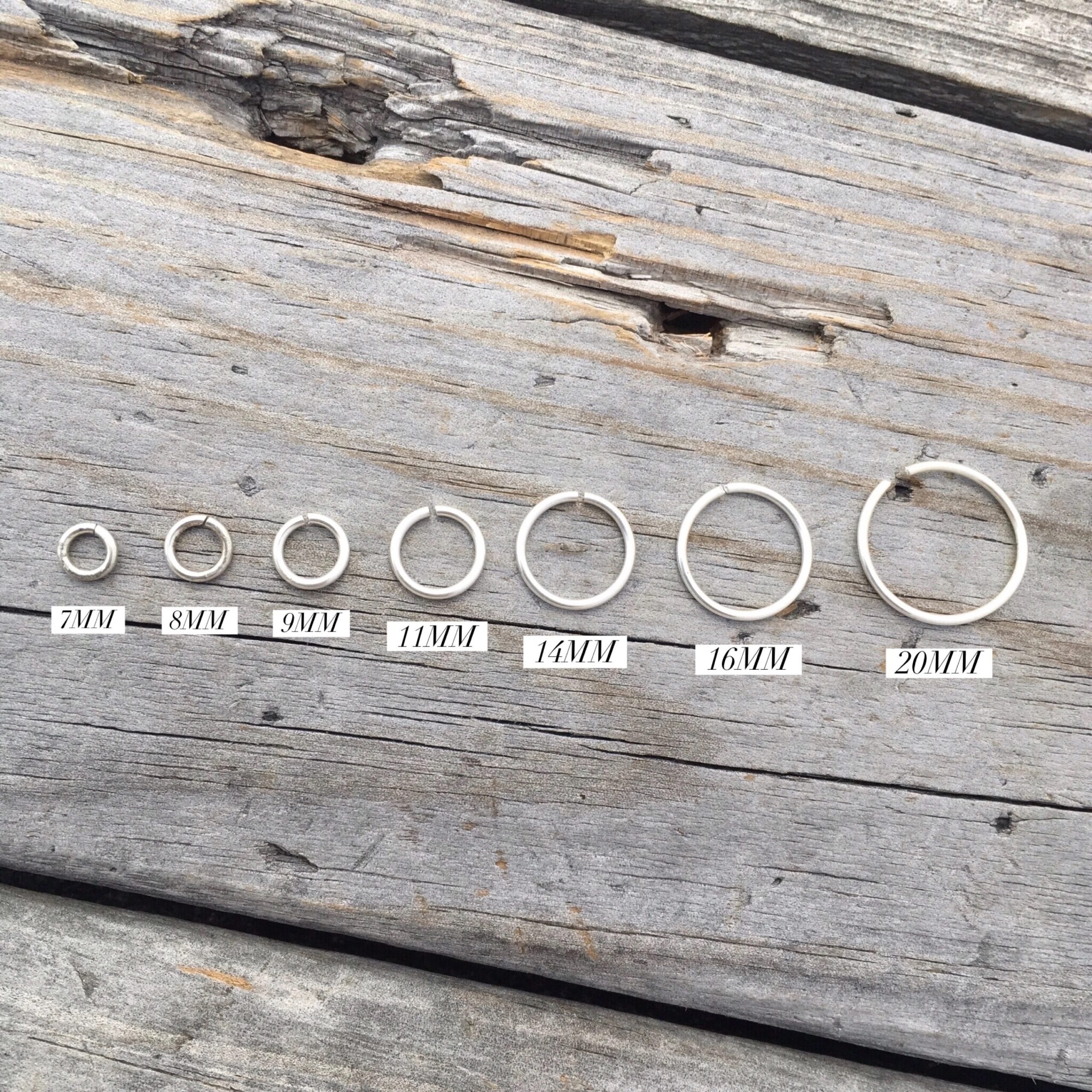 Seven jump rings labeled with mm and going from smallest to largest left to right.