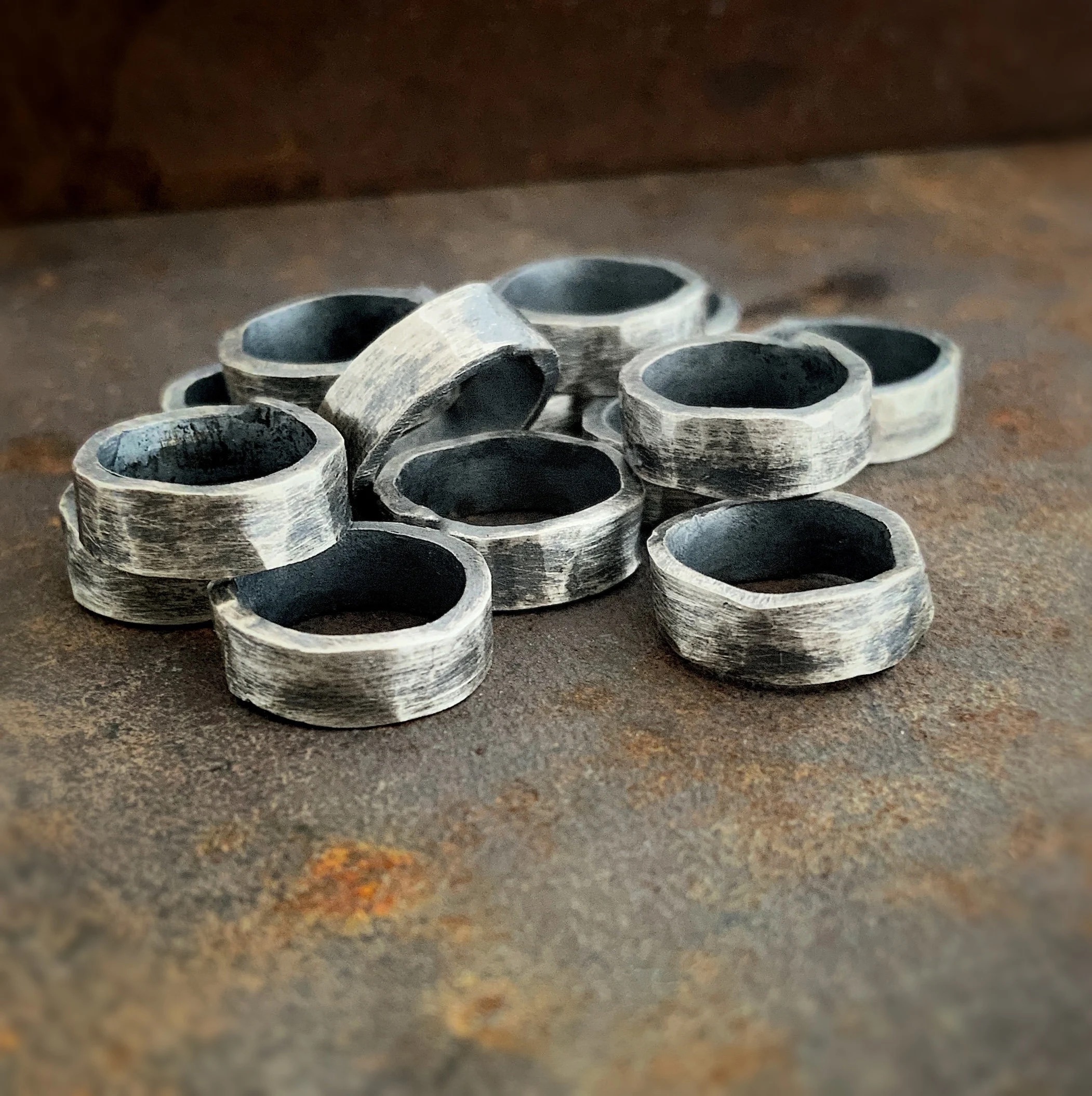 Image 27 Pile of thick oxidized jump rings against a rusted metal background.