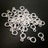 Pile of sterling silver double jump rings that are shiny against a dark background.