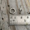 Two soldered oxidized jump rings shown against a ruler to demonstrate size and width.